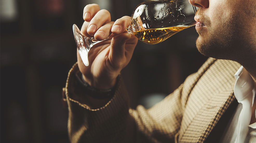 Close-up photo of sommelier tasting whiskey taste on the cellar background